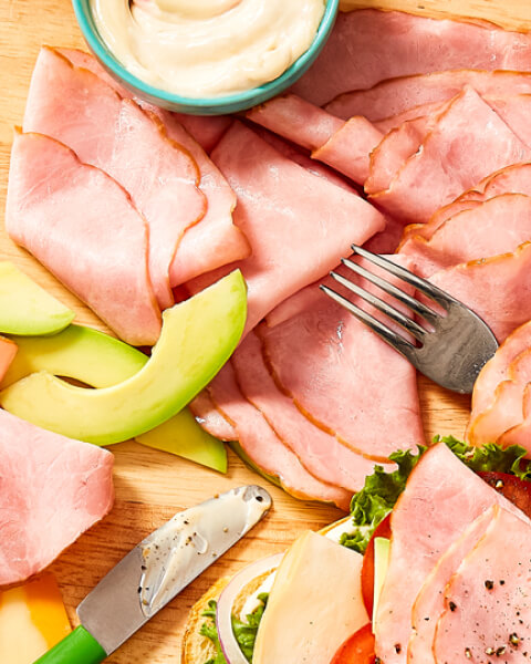 Compliments_Deli_Meat Overhead shot of all natural deli-meats on cutting board with sliced avocados