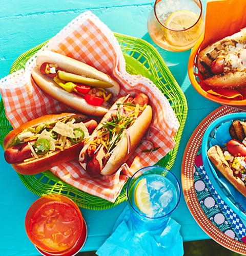 hotDogs Blue tabletop with 4 plates of the 7 hot dogs.